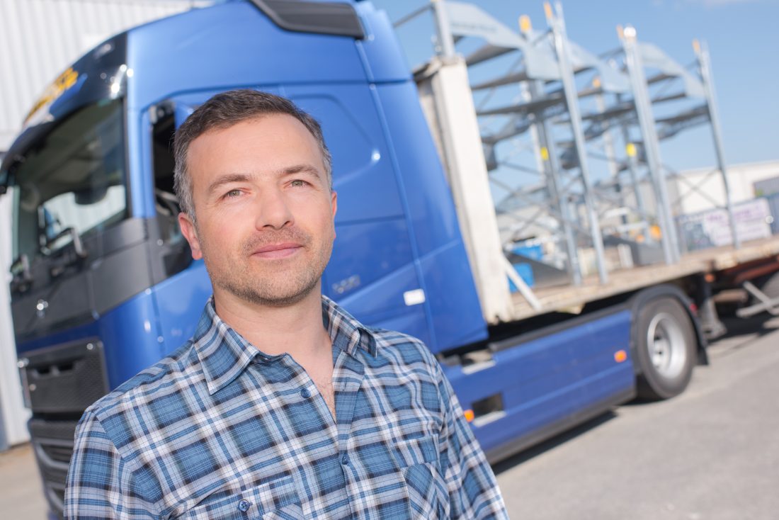 successful trucking company owner in front of a truck
